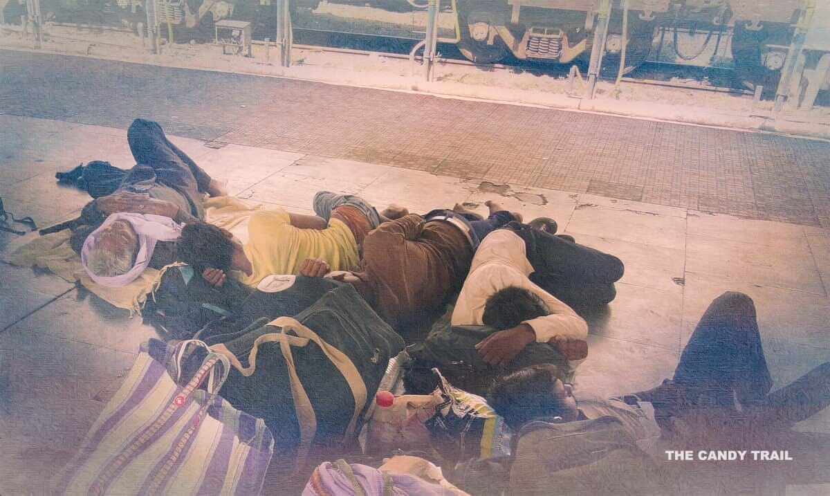 men sleeping on platform of railway station in india.