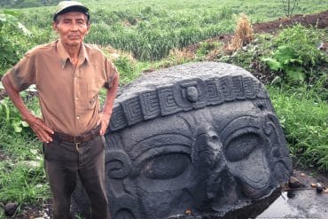 sugarcane worker beside giant stone head guatemala