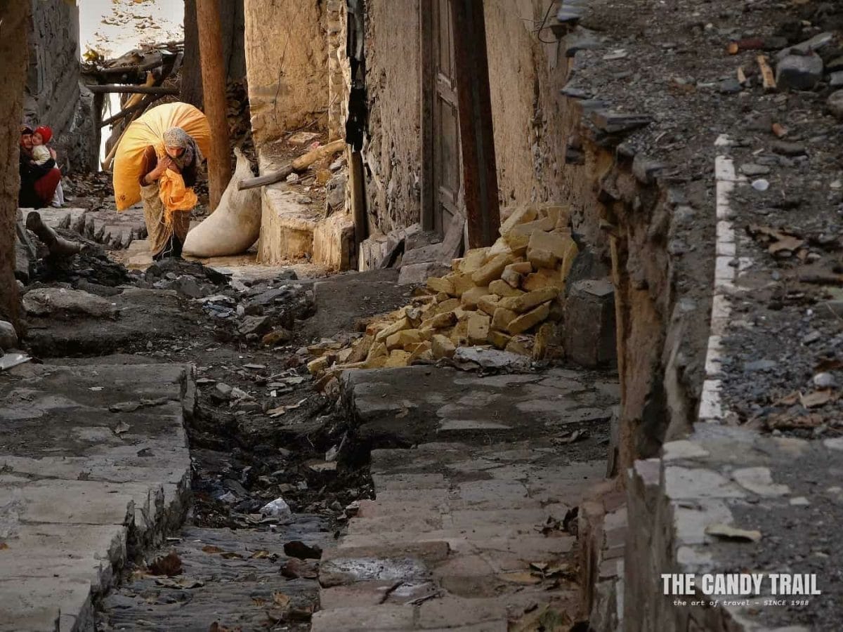 Women lugs up a huge bag steep, stepped lanes of Kang village Iran