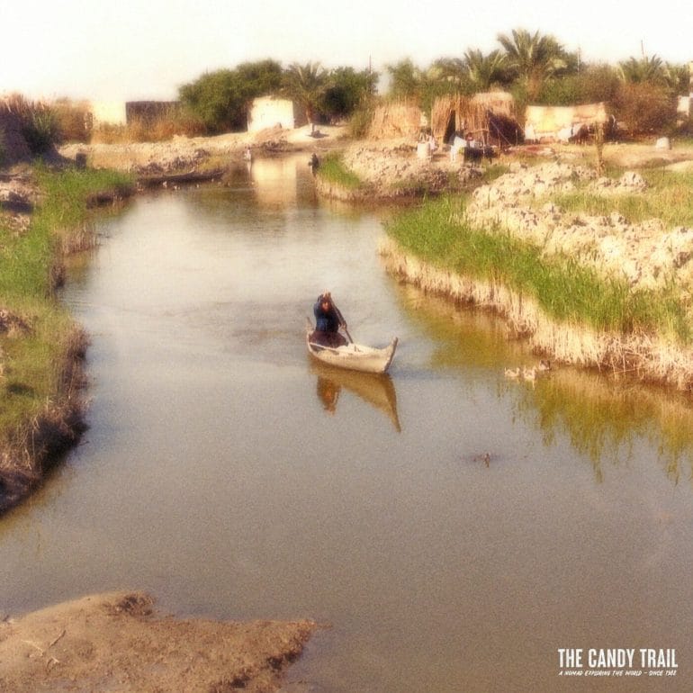 women paddles canoe amid rivers of marsh arab village in iraq 1989