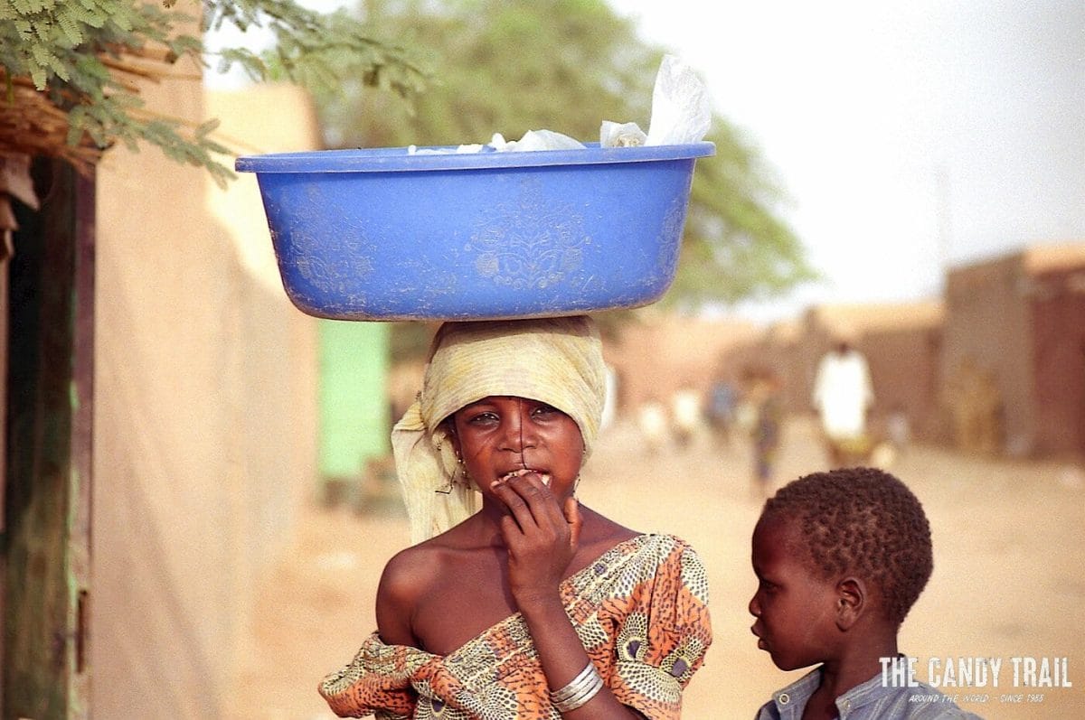 young girl balances bowl on head in streets of zinder in niger